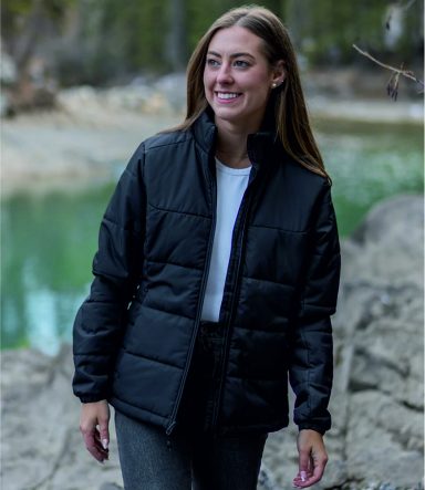 Jackets Smiling woman wearing a black quilted jacket by a riverbank.